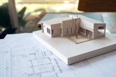 Ofisteki masasında bulanık bir geçmişi olan kağıt ve dizüstü bilgisayarı olan bir mimari modeli.