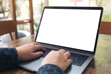 Kafe 'deki boş beyaz masaüstü ekranı ile laptopta yazı yazan ve kullanan ellerin görüntüsü