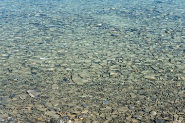 Göldeki mavi suyun altındaki taşın yakın plan görüntüsü.