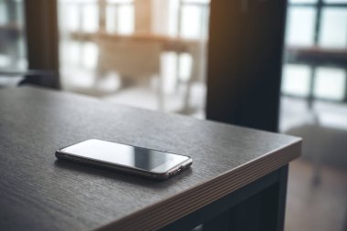 Ofisteki ahşap masada tek bir cep telefonu.