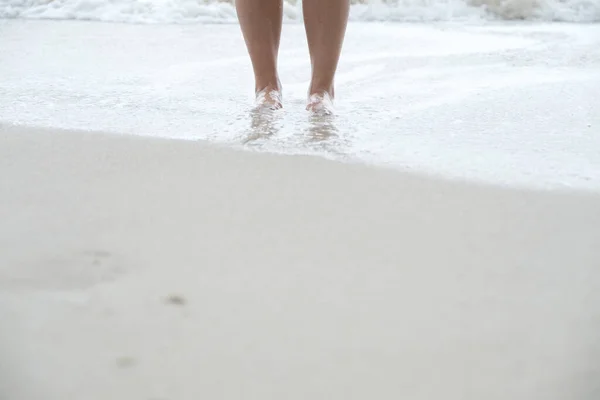 站在白沙滩和大海上的人的腿的塑像 — 图库照片