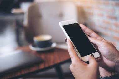 Kafedeki boş siyah masaüstü ekran ile cep telefonu tutan kadınların ellerinin görüntüsü