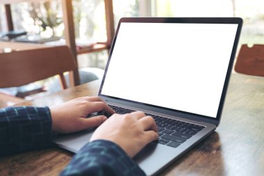 Kafe 'deki boş beyaz masaüstü ekranı ile laptopta yazı yazan ve kullanan ellerin görüntüsü