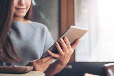 Güzel bir Asyalı kadının elleri kafede tablet tablet kullanıyor.