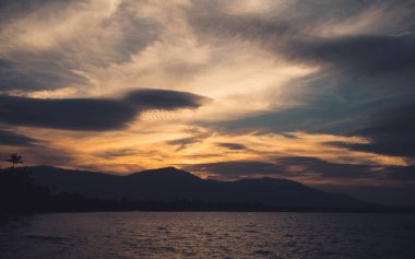 Deniz ya da okyanus manzarası ve akşam vakti çok güzel bir geçmişi olan dağ.