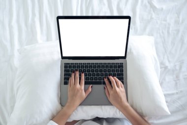 Üst görünümde, boş beyaz masaüstü ekran klavyeli dizüstü bilgisayarı kullanan ve yazan bir kadının görüntüsü 