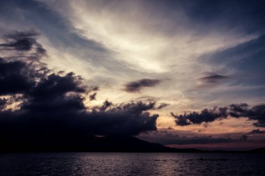 Akşamdan önce güzel bir geçmişi olan deniz, okyanus ve dağın görüntüsü.