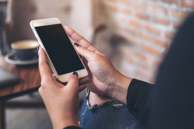Kafedeki boş siyah masaüstü ekranlı beyaz cep telefonu kullanan ve el ele tutuşan bir kadının görüntüsü.