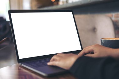 İş kadınının laptopta boş beyaz masaüstü ekran ve kafedeki ahşap masada kahve fincanı kullanarak ve yazarak görüntüsü.