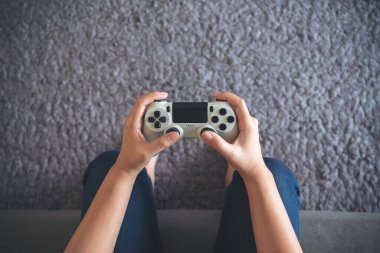 Oyun oynarken oyun denetleyicisini tutan ellerin üst görünüm resmi 