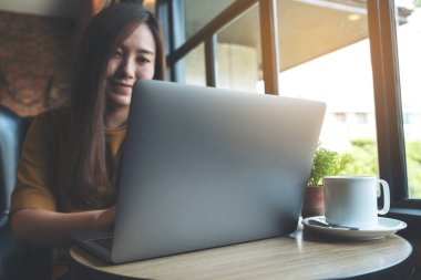 Kafedeki dizüstü bilgisayarda çalışan ve daktilo kullanan Asyalı güzel bir kadının yakın plan görüntüsü.