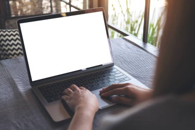 Masada boş beyaz masaüstü ekranı olan bir kadının ellerini laptopta yazarken ve kullanırken görüntüle