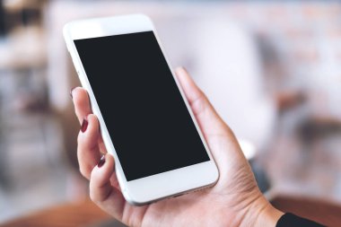 Boş siyah masaüstü ekranı ve bulanık arkaplanı olan beyaz cep telefonunu tutan bir elin görüntüsü