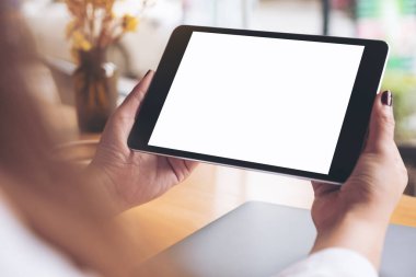 Siyah tabletli, beyaz masaüstü ekranlı ve kafedeki ahşap masadaki dizüstü bilgisayarlı kadınların ellerinin görüntüsü.