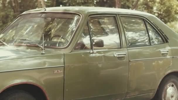 Un giovane vestito nello stile degli anni '80 cammina vicino alla vecchia auto verde sovietica dei tempi dell'URSS, guarda in lontananza, cammina verso l'auto e apre la porta. — Video Stock