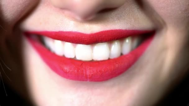 Sorriso brilhante sedutor da menina close-up, batom vermelho nos lábios, neve-branco mesmo dentes untados com batom vermelho, uma mulher sorri, brinca morde seu lábio — Vídeo de Stock