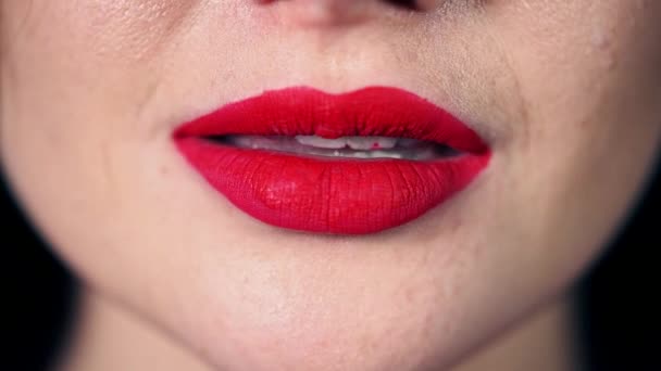 Seductive bright smile of the girl close-up, red lipstick on the lips, snow-white even teeth smeared with red lipstick, a woman smiles, playfully bites her lip — Stock Video