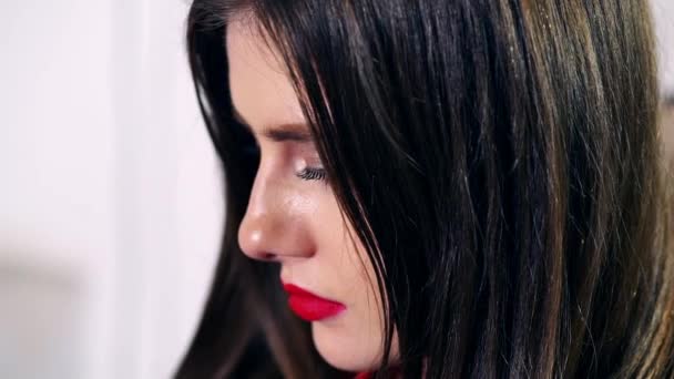 Sexy brunette met lichte make-up en rode sappige lippen is liggend op een leerbank, op zoek naar de kant, belangrijke dingen na te denken, denken over het leven, kijken naar de telefoon — Stockvideo