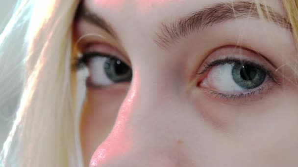 Olhos de uma menina close-up. Olha para a câmara. Sardas no rosto das mulheres. Bonito rosto menina bonita e maquiagem leve. Movimento lento — Vídeo de Stock