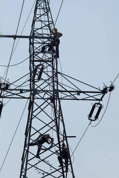 Electrician repair of electric power system. Electrician stays on the tower pole and repairs power line.