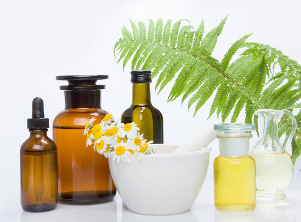 Healing herbs with mortar and bottle of essential oil.