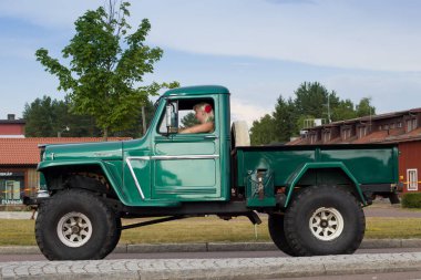 Rattvik, İsveç - 27 Temmuz 2013: Land Rover Defender, Women and offroad vintage truck car 4x4 Classic Car Week. Bir kadın büyük bir kamyonet kullanıyor. Eski araba kamyonu..