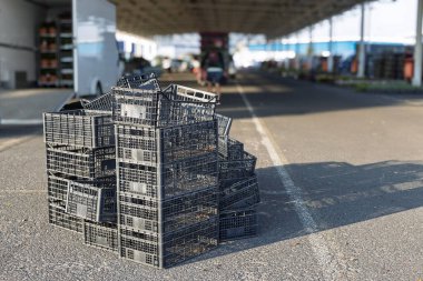 Stack of empty black plastic crates at market