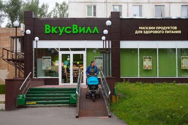 Moscow, Rusya Federasyonu - 24 Temmuz 2018: Vkusvill gıda deposunda bina ve kadın bebek arabası ile Muranovskaya sokağa. Bu sokak, Bibirevo bölge Moskova'da bulunan.