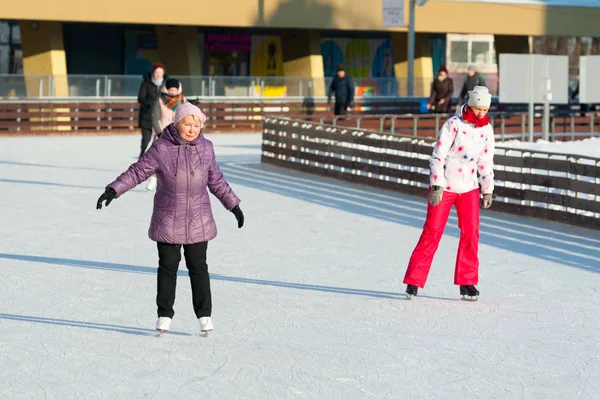 俄罗斯莫斯科 2019年1月22日 冬季阳光明媚的日子里 Vdnkh 穿红色溜冰的老年妇女和成年女子 Vdnkh 是永久的通用贸易展和游乐园 — 图库照片