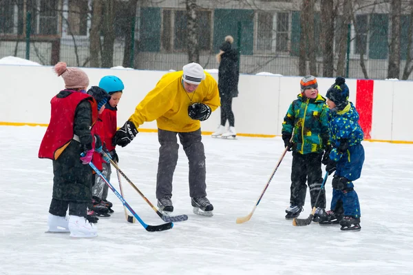 俄罗斯莫斯科 2019年1月26日 成年男子向孩子们解释如何在冬季在贝洛泽尔斯卡亚街的溜冰场打曲棍球 这个溜冰场位于莫斯科北部的比比雷沃区 — 图库照片