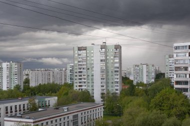 Moskova 'da bahar günü fırtınalı gökyüzüne karşı binalar ve yeşil ağaçlar