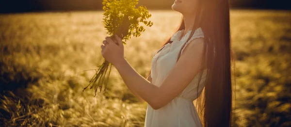 夏日的黄昏时 田野里的草在夕阳西下时 一个女孩跑过田野采花 — 图库照片