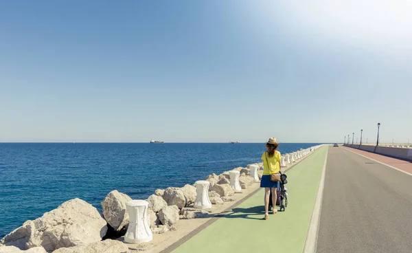 Moeder wandelen met pasgeboren in een lange kustweg — Stockfoto