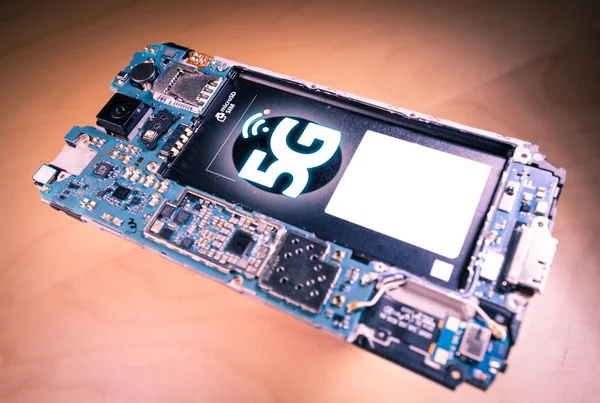Disassembled mobile phone or smartphone without a back cover, and 5G or LTE word printed in circuit board — Stock Photo, Image