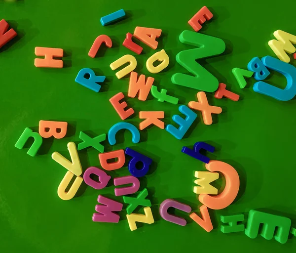 Colorful alphabet magnets on a green board.