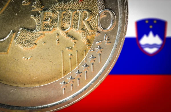 2 Euro coin with a blurred flag of Slovenia on the background — Stock Photo, Image