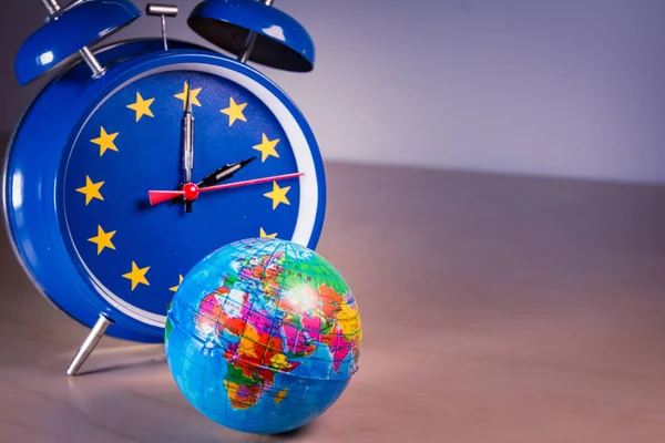 Retro alarm clock with the colors of the EU flag for an hour and planet earth ball — Stock Photo, Image