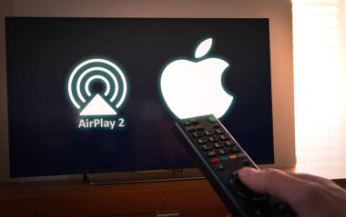 Barcelona, İspanya. Ocak 2019: Adam bir uzaktan kumanda ile elma ve Airplay2 simge ekran televizyonda tutar