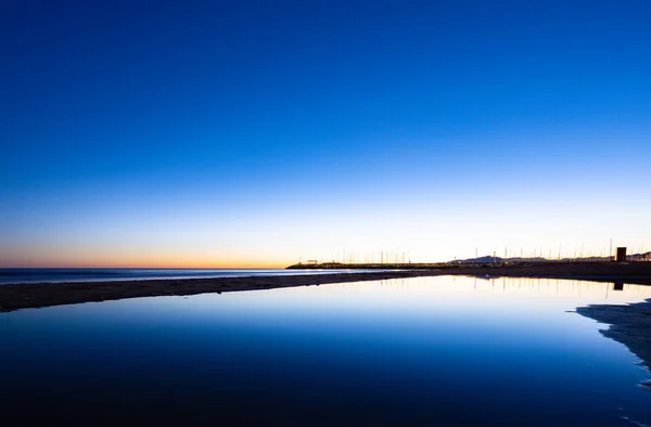 Hora azul de la puesta de sol de la playa de invierno con aguas espejo —  Fotos de Stock