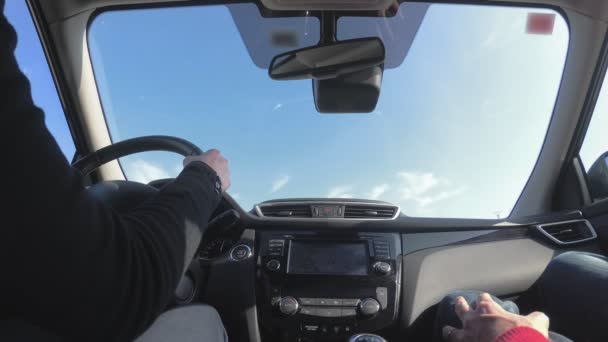 Mujer conduciendo un coche a lo largo de la carretera, el sol brilla en el parabrisas. vista de ángulo bajo — Vídeos de Stock