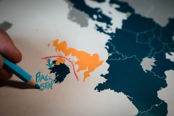 Hand drawing a red line between the UK and Northern Ireland, Backstop and Brexit concept.