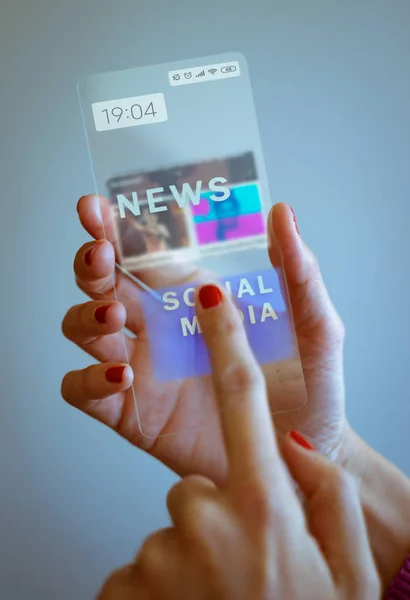Frau hält transparentes Smartphone in der Hand und berührt den Bildschirm — Stockfoto