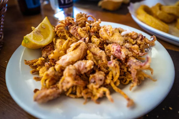 Plate of deep fried squids or Chipirones with lemon. Typical spanish tapa — Stock Photo, Image