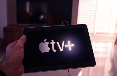 Barcelona, İspanya. Mart 2019: Adam bir tablet ile belgili tanımlık yeni elma Tv artı ekran üzerinde tutar.