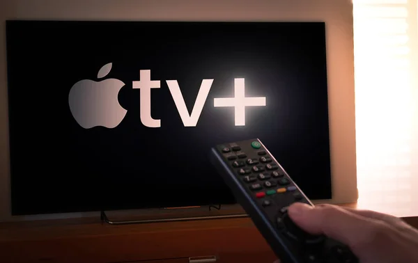 Barcelona, Spanyol. Maret 2019: Man memegang remote control Dengan layar Apple TV + baru di TV — Stok Foto