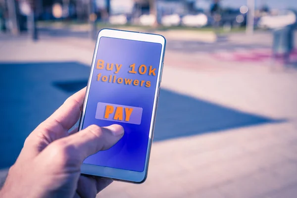 Hände mit einem Smartphone mit dem Kauf Follower Bezahlung auf dem Bildschirm. — Stockfoto