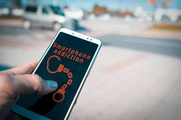 Руки с помощью смартфона с наручниками и слова зависимость смартфона на экране — стоковое фото