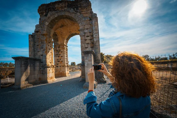 Mujer turista tomando una foto con cámara del Arco de Caparra, antigua ciudad romana de Caparra en Extremadura, España — Foto de Stock