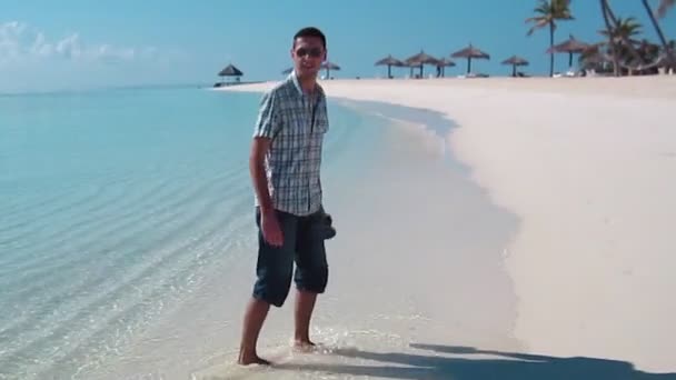 Όμορφος άνδρας φορώντας λευκά ρούχα που θέτουν σε τοπίο στη θάλασσα — Αρχείο Βίντεο