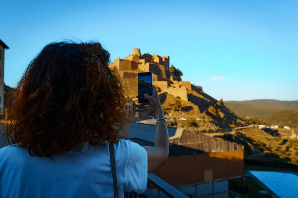 Chica turística tomando una foto con un smartphone del castillo medieval de Cardona en Cataluña, España — Foto de Stock